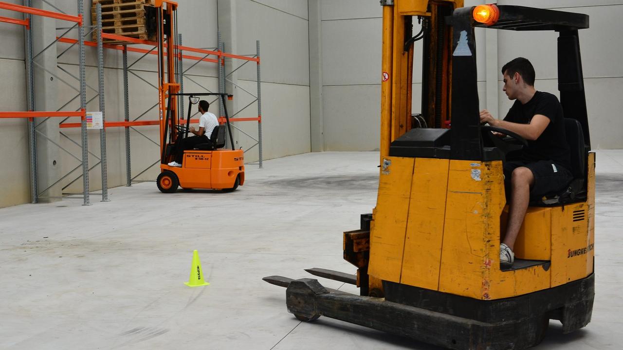 Foto de um galpão com uma empilhadeira em primeiro plano; no fundo, mais uma empilhadeira levantando pallets.